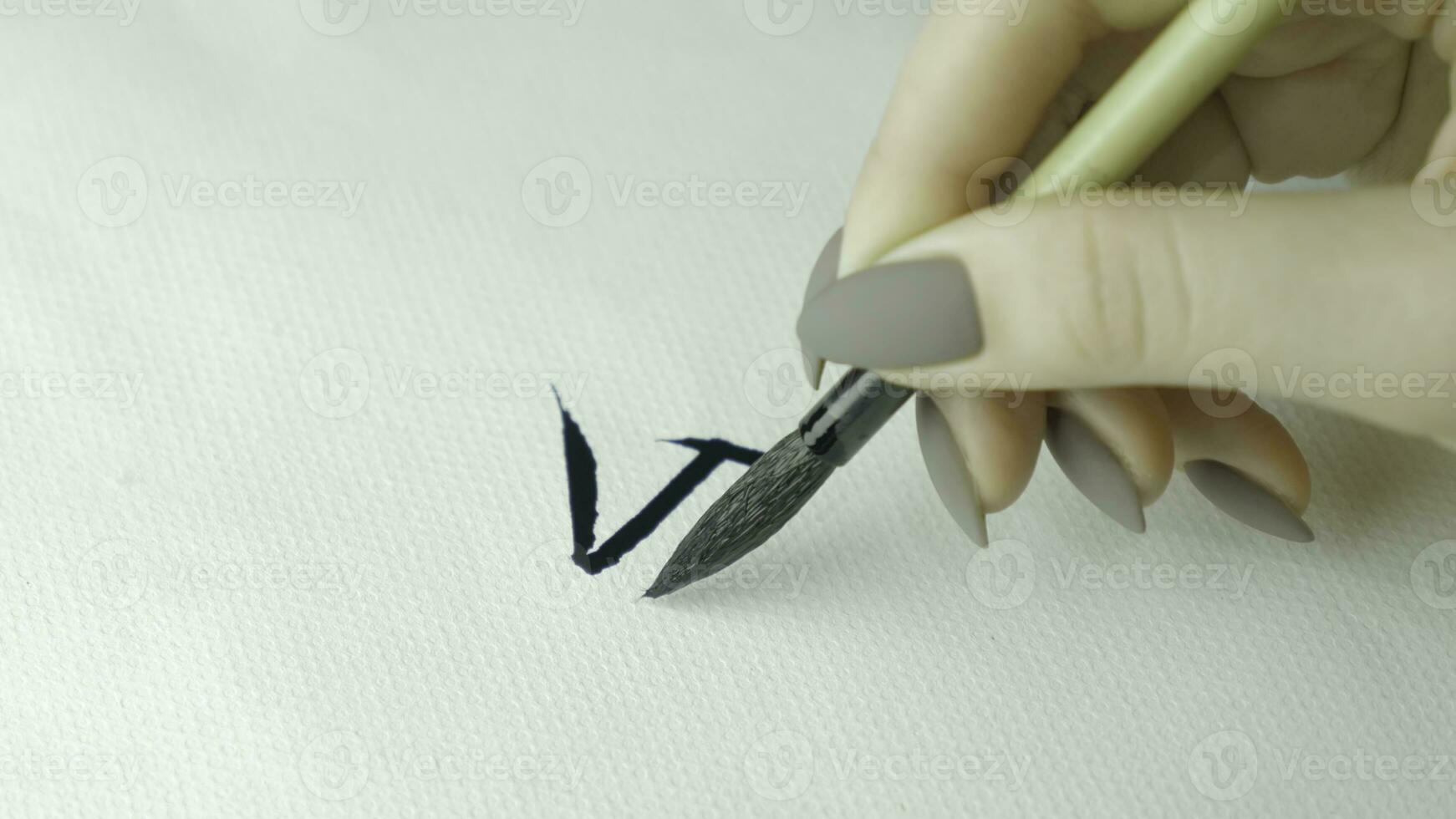 Woman's hands writing Chinese hieroglyph. Female hand holding a writing brush calligraphy Chinese characters, close up photo