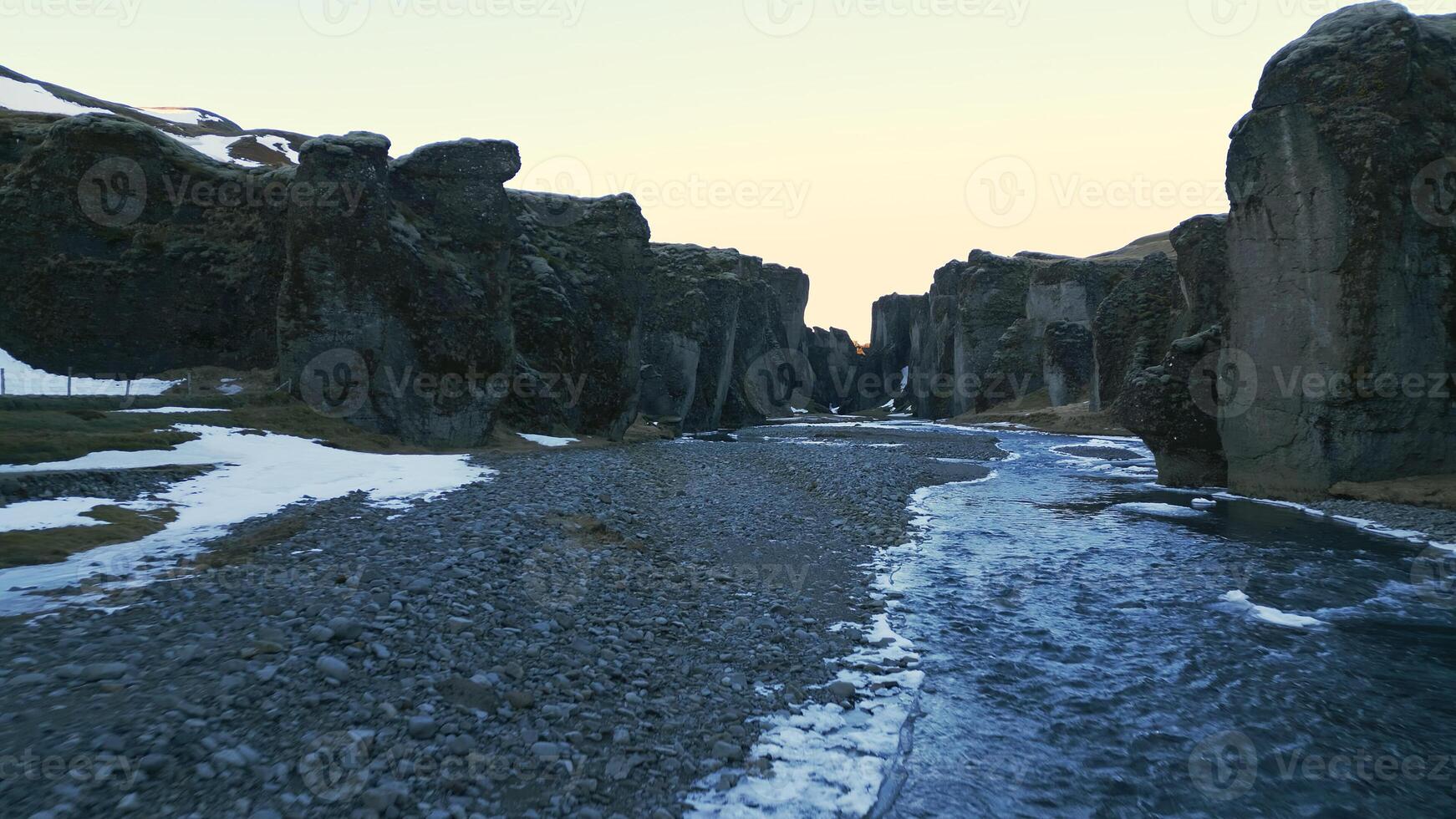 Icelandic fjadrargljufur canyon drone shot with beautiful river and nordic landscapes, snowy mountains and hills. Roadside arctic scenery with water flowing between rocks and cliffs. Slow motion. photo