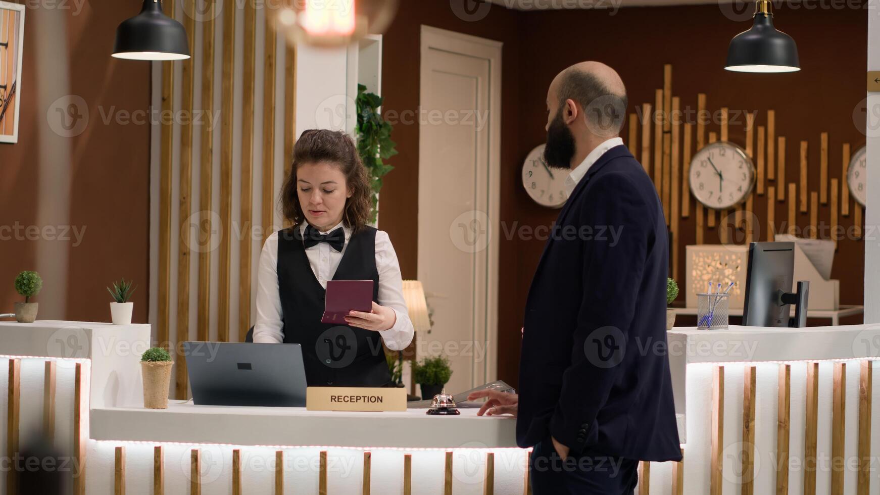 Hotel concierge verifying passport id for guest identification, preparing to fill in registration forms. Receptionist looking at credentials after greeting company entrepreneur in reception lobby. photo
