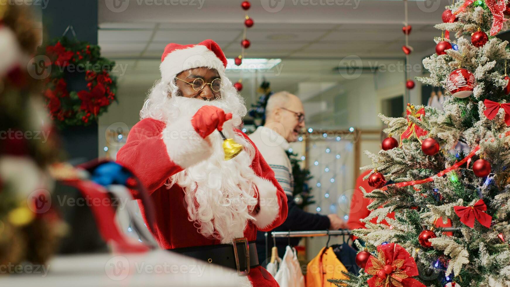 Employee acting as Santa Claus entertaining shoppers in Christmas decorated fashion store during winter holiday season. Worker instilling festive spirit in clients visiting clothing shop photo