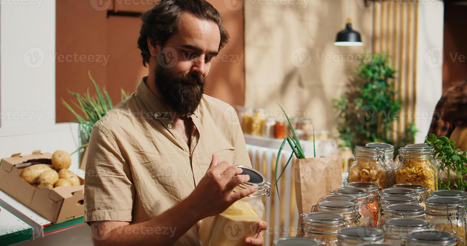 Man in zero waste shop checking products before making purchase decision, making sure they are natural, dolly in shot. Client verifying pantry staples displayed in local neighborhood store are organic photo