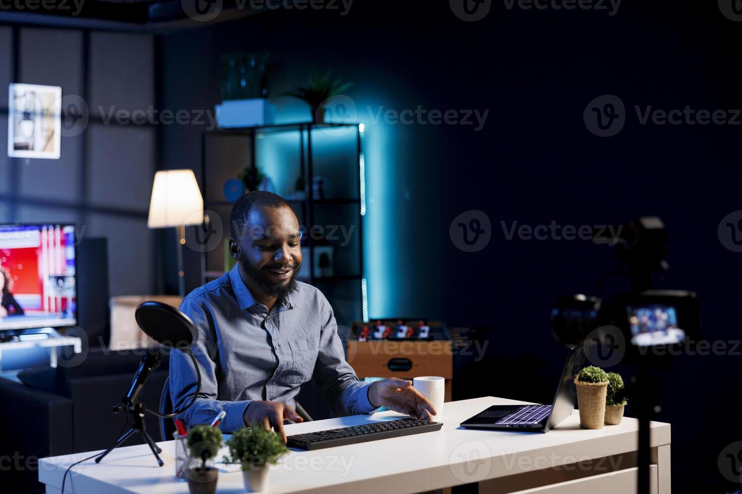 Influencer in studio using camera to capture live broadcast, reviewing gaming keyboard. BIPOC online show host filming electronics haul, presenting wireless computer peripheral to viewers photo