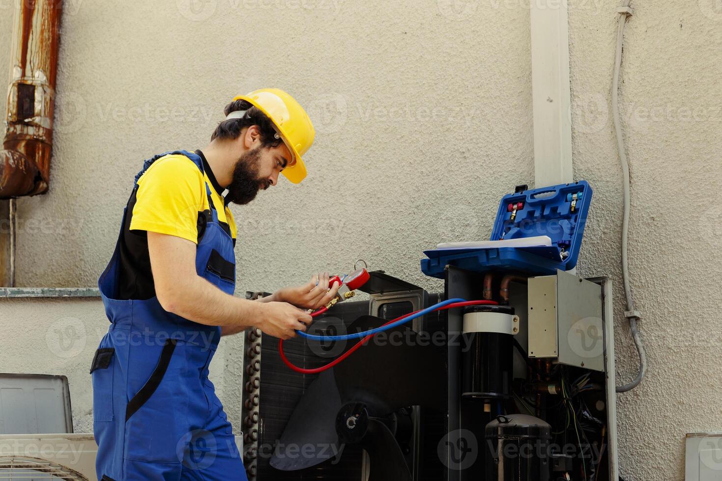 Capable serviceman hired to check external air conditioner freon tank in need of troubleshooting, using manometers. Qualified technician using manifold gauges looking at condenser refrigerant levels photo