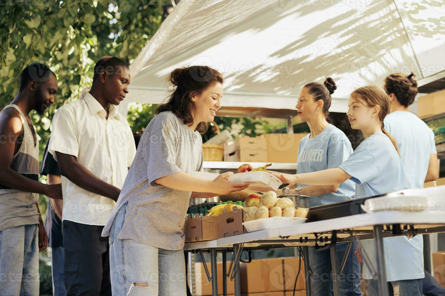 Charity workers helping homeless, refugees and the needy by distributing food outdoors. Hunger relief and assistance are provided to people in poverty through nonprofit organization. photo