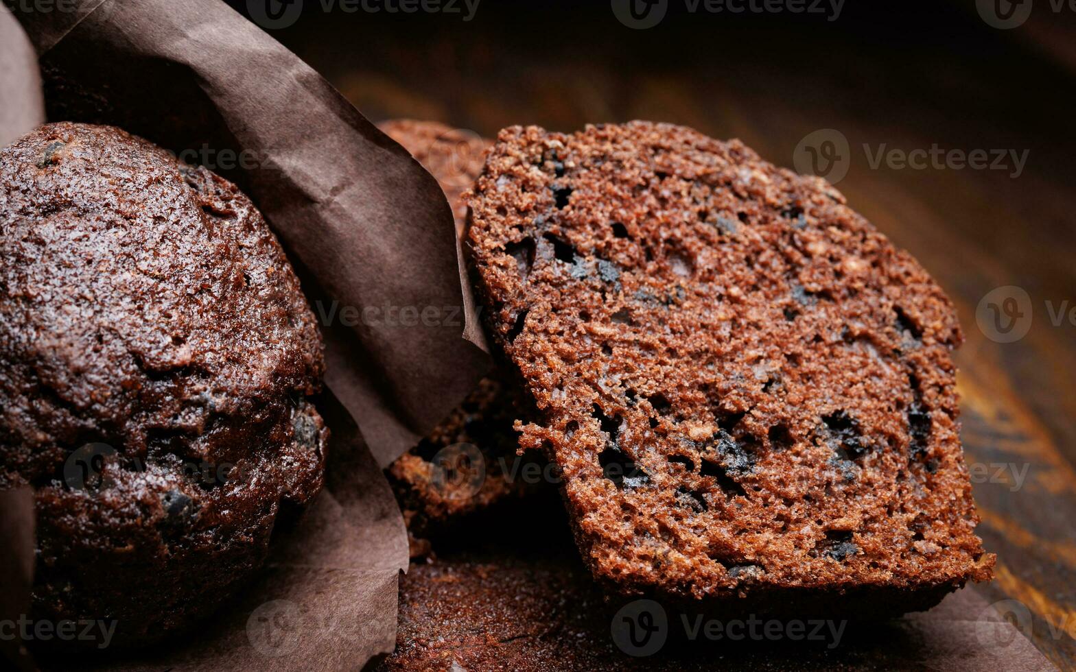 Whole and halved chocolate cupcake on a dark background. Muffin with chocolate chips on dark paper. photo