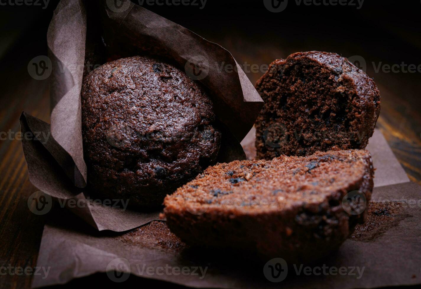 Whole and halved chocolate cupcake on a dark background. Muffin with chocolate chips on dark paper. photo