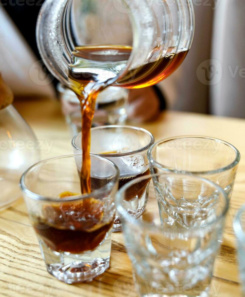 café es vertido desde un vaso cervecero dentro vaso lentes. foto