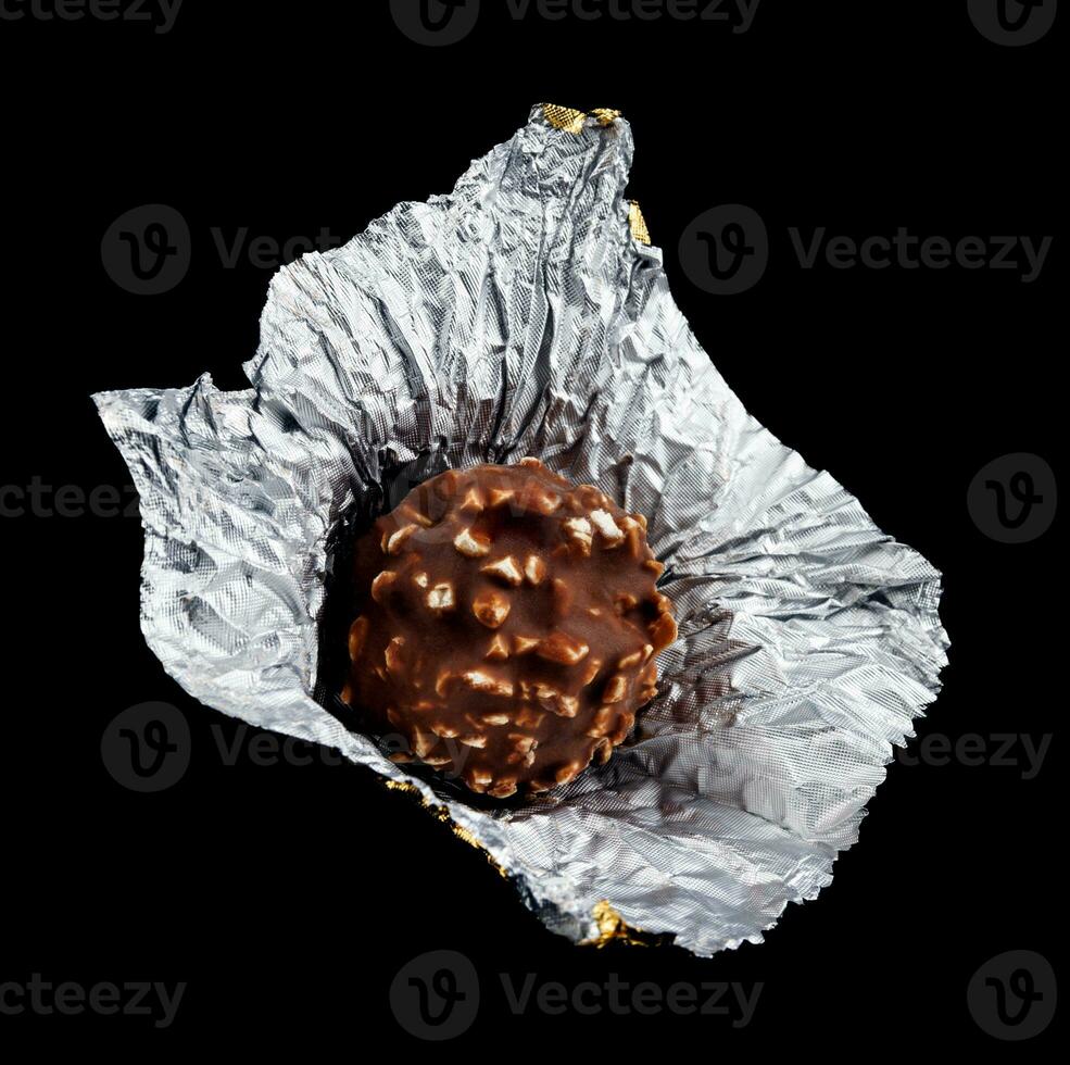 Unwrapped chocolate candy in foil on a black background. photo