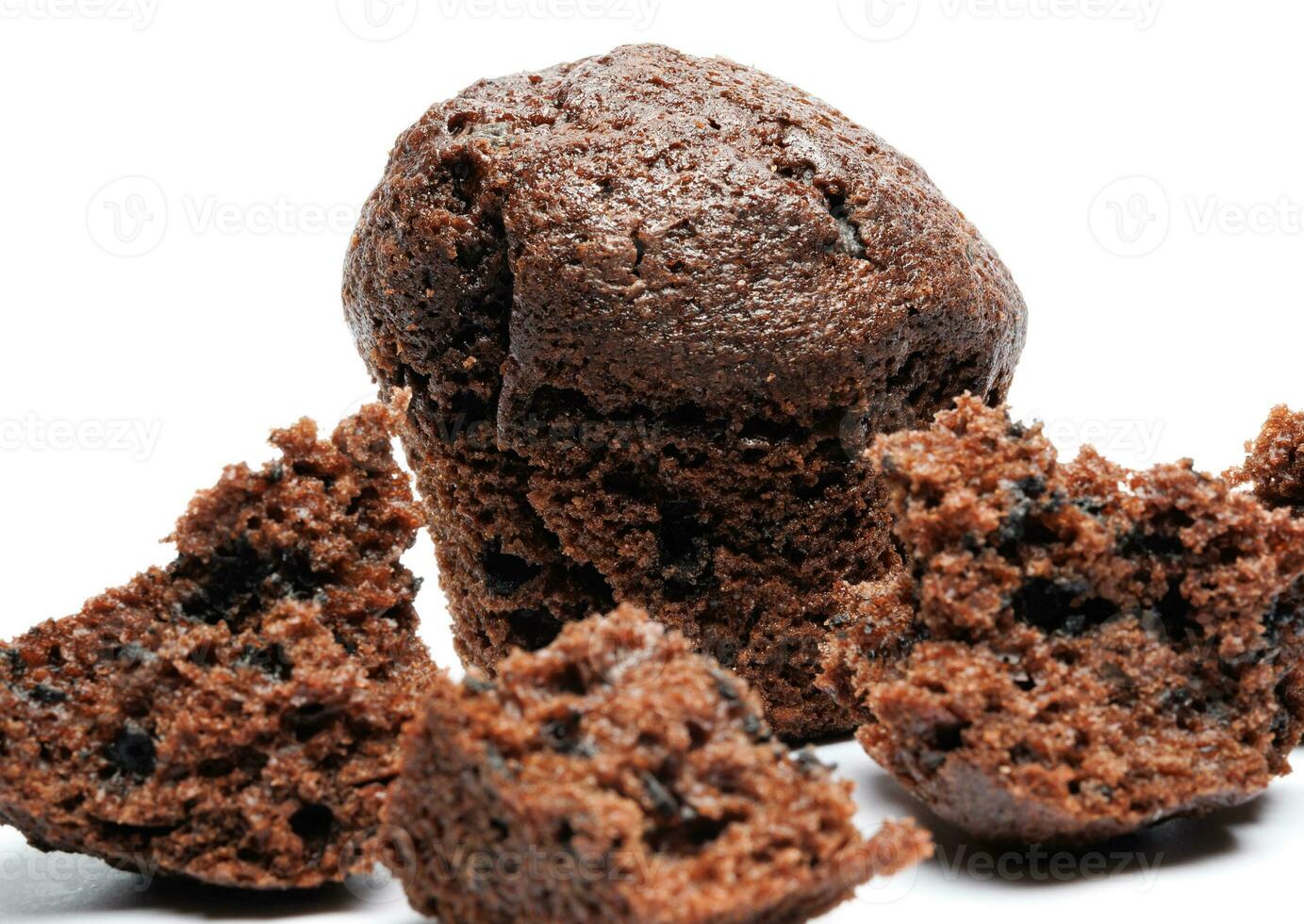 Whole and broken into pieces chocolate muffin isolated on a white background. Chocolate chip muffin. photo