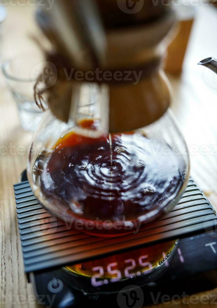 Coffee is brewed in a glass container through a paper filter, circles on the surface from falling drops. photo