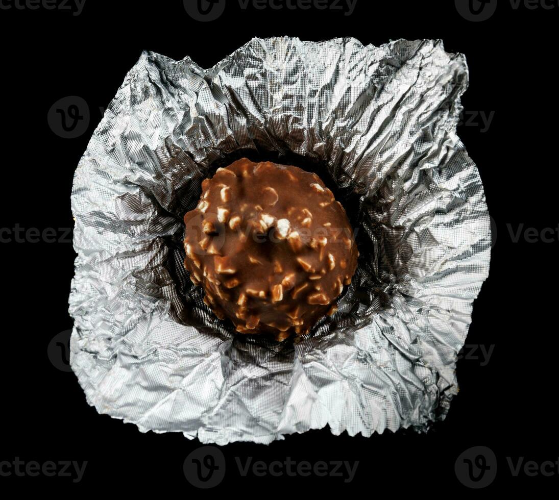 Unwrapped chocolate candy in foil on a black background. photo