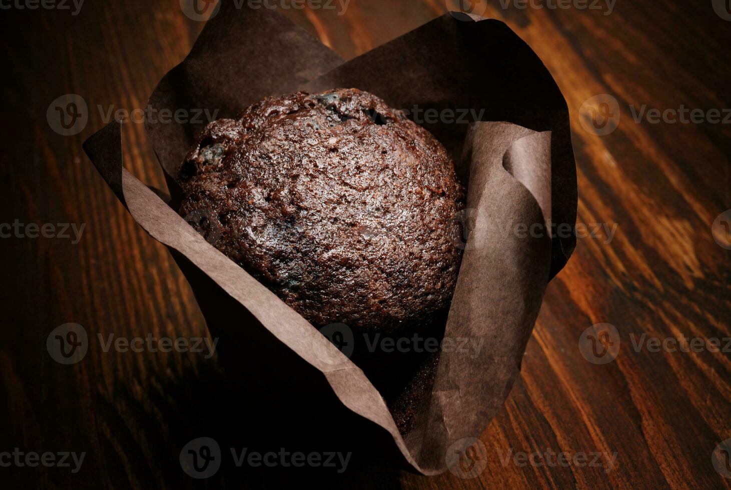 Chocolate cupcake on a dark background. Muffin with chocolate chips on a wooden surface. photo