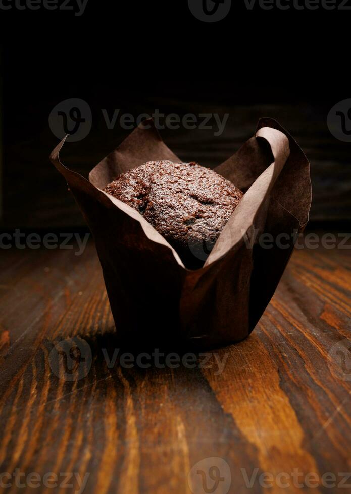 Chocolate cupcake on a dark background. Muffin with chocolate chips on a wooden surface. photo