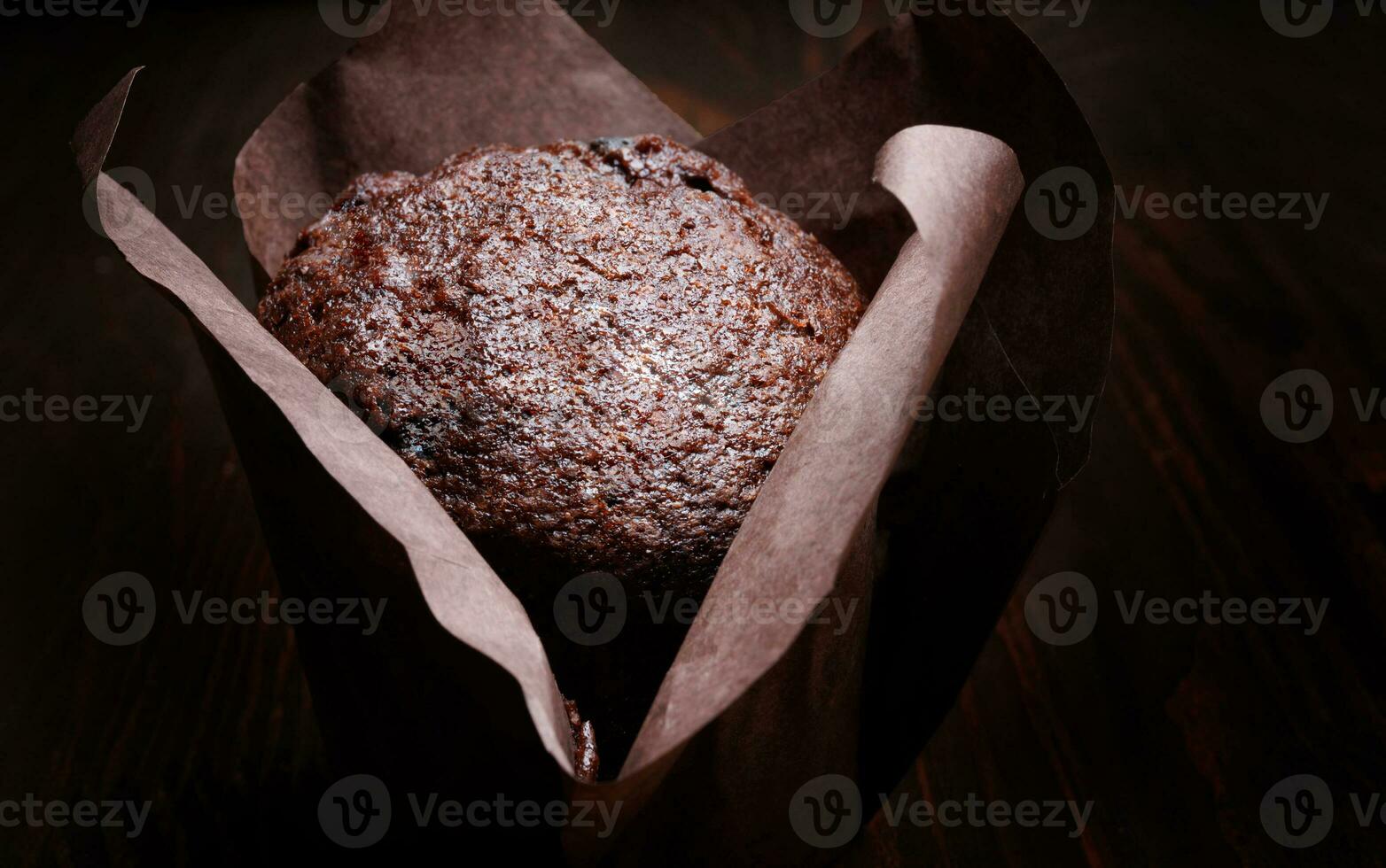 Chocolate cupcake on a dark background. Muffin with chocolate chips on a wooden surface. photo