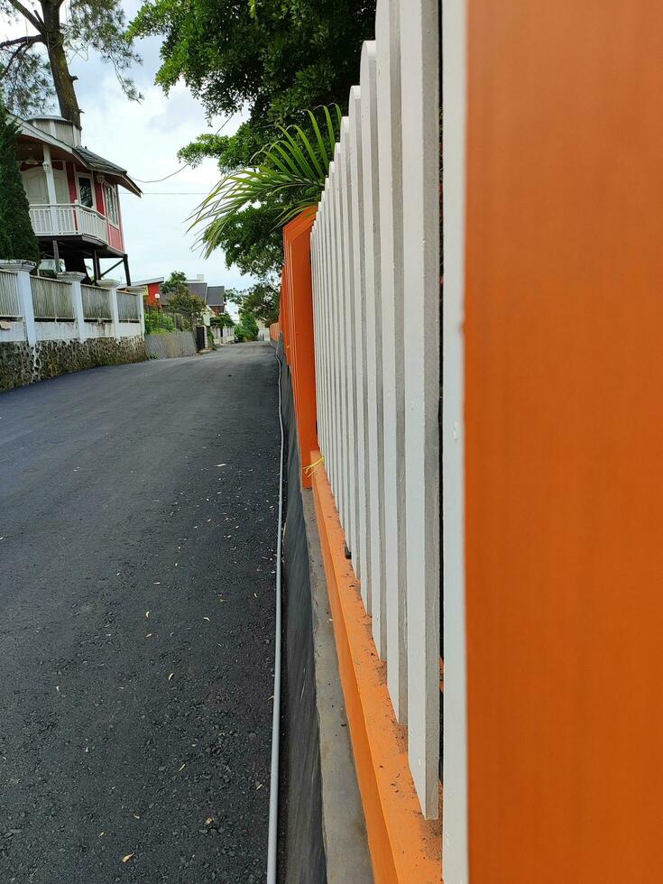 orange and white wall fence on the edge of a beautiful rural asphalt road photo