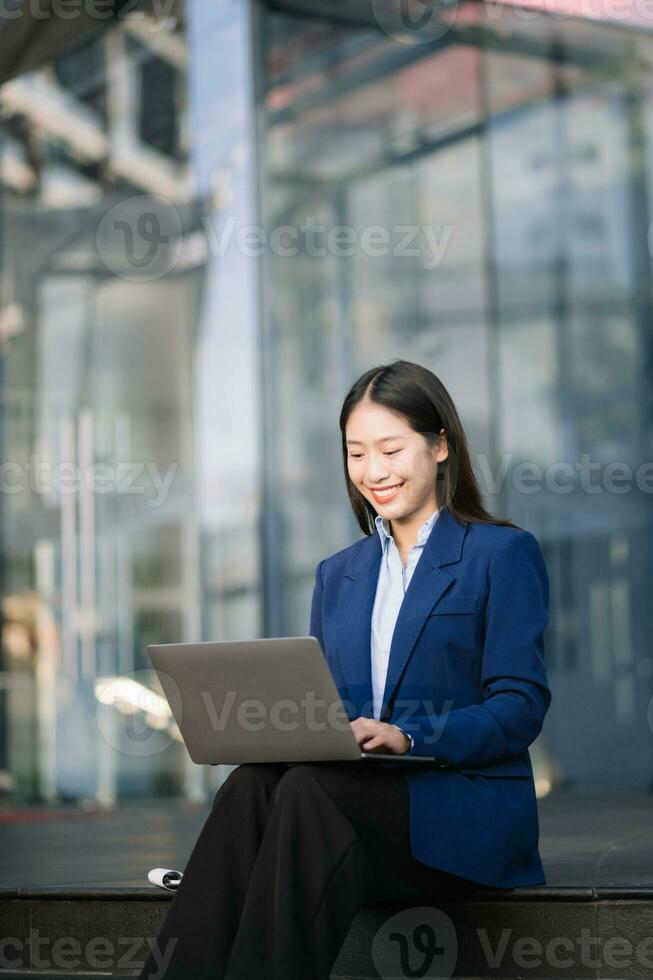 Confident Asian woman with a smile standing holding notepad and tablet at out side office photo