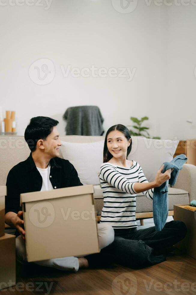 Asian young attractive couple man and woman use tablet and smartphone online shopping furniture decorate house with carton package move photo