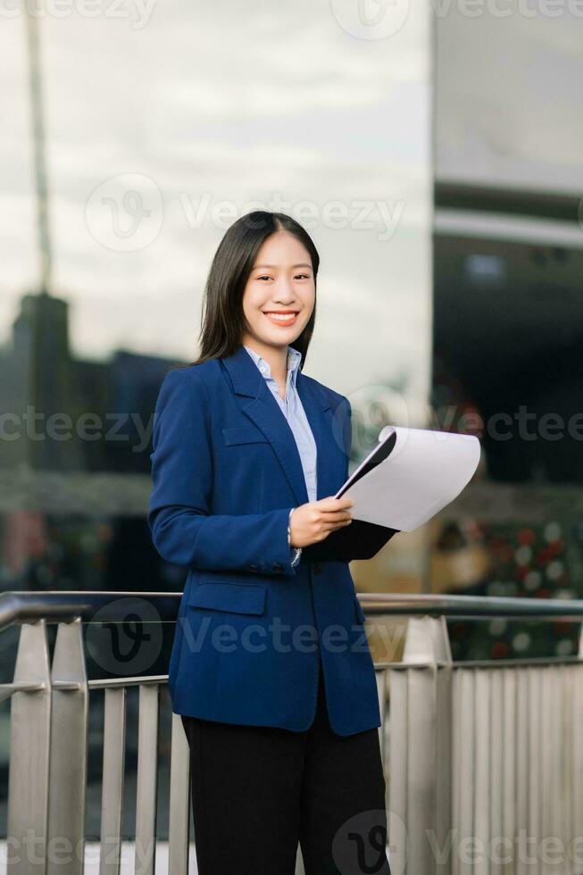 Young Asian business woman leader entrepreneur, professional manager holding digital tablet computer uon the street in big city photo