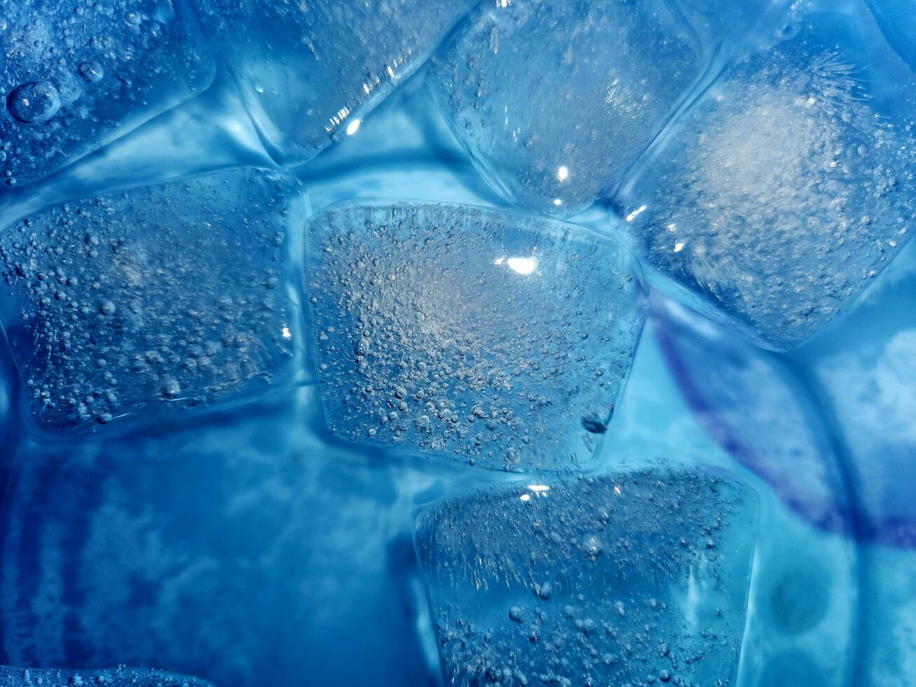 Ice cubes isolated on blue background photo