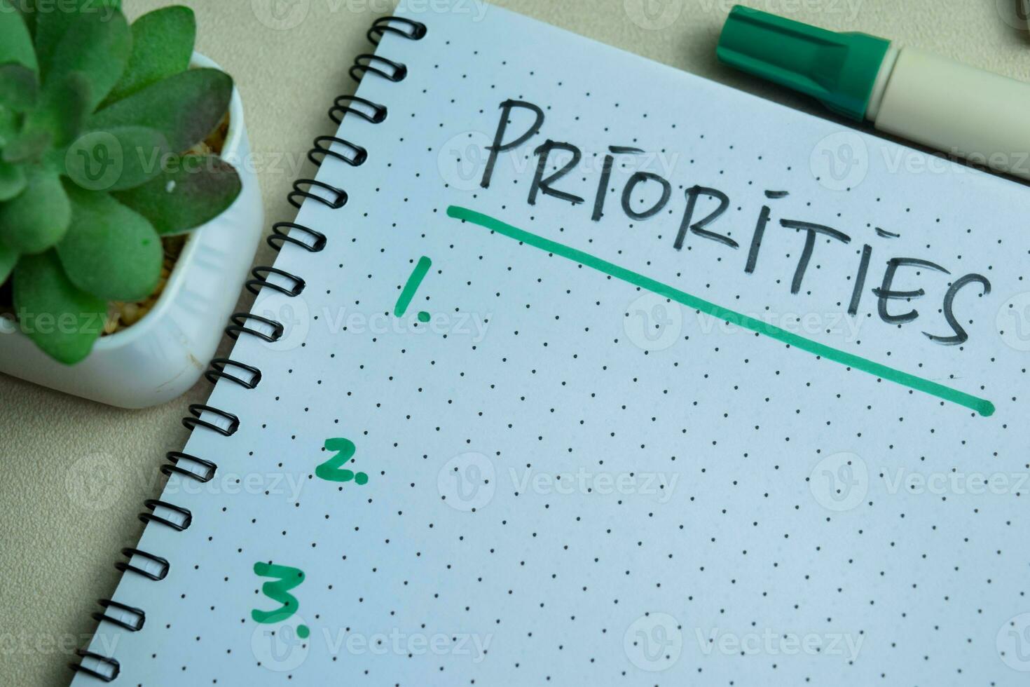 Concept of Priorities write on book. Supported by an additional services isolated on Wooden Table. photo