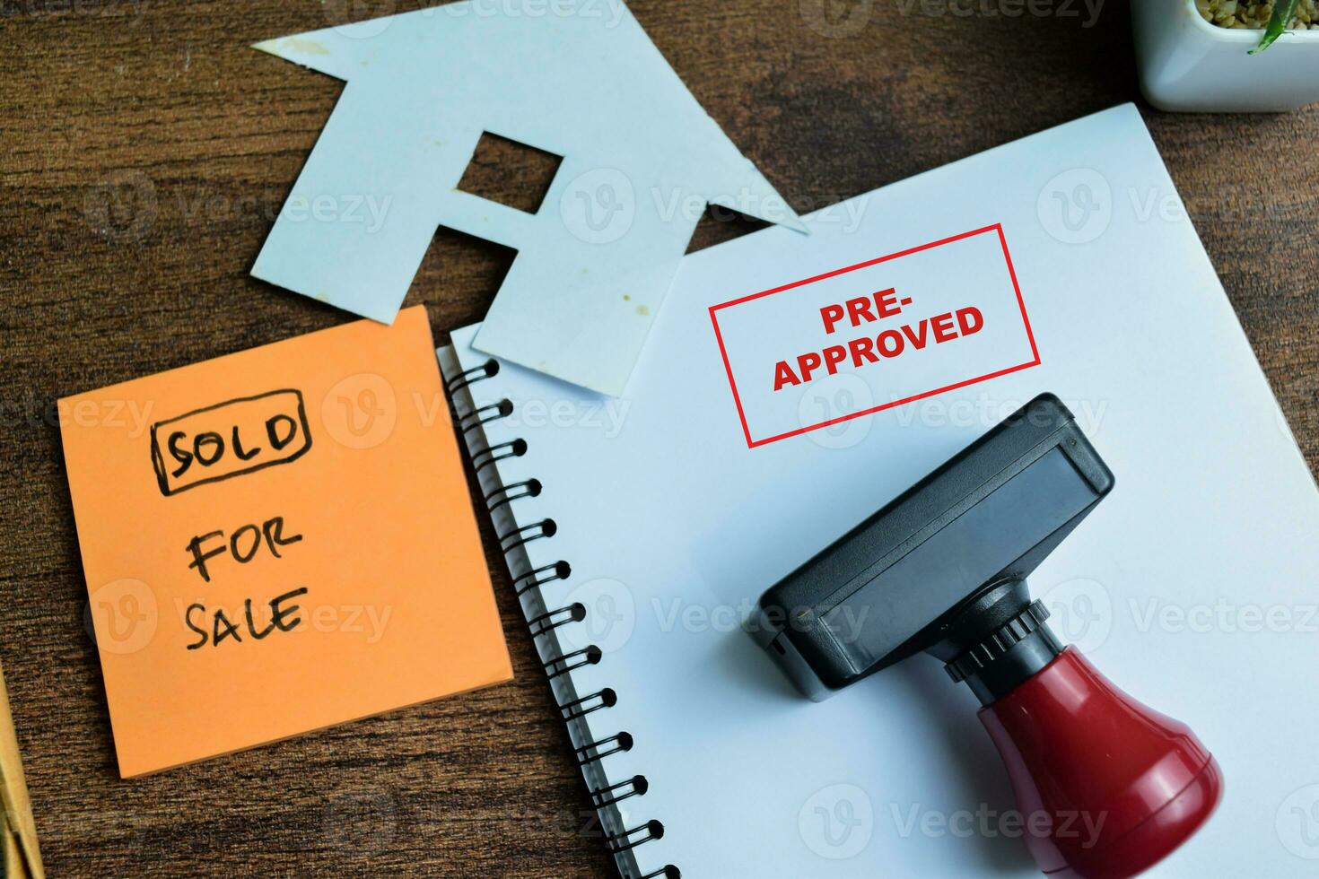 Red Handle Rubber Stamper and Pre-Approved text and Sold For sale above book isolated on wooden background photo