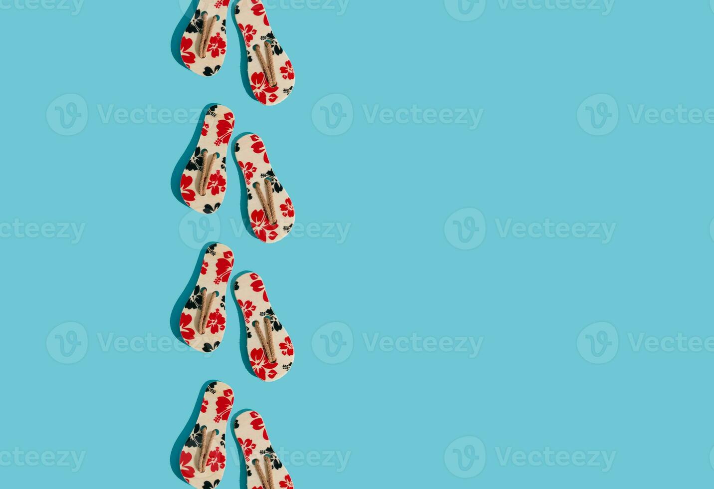 Creative sunlight summer composition made with floral slippers on bright blue background with copy space. Minimal summer concept. Trendy summer vacation idea. photo