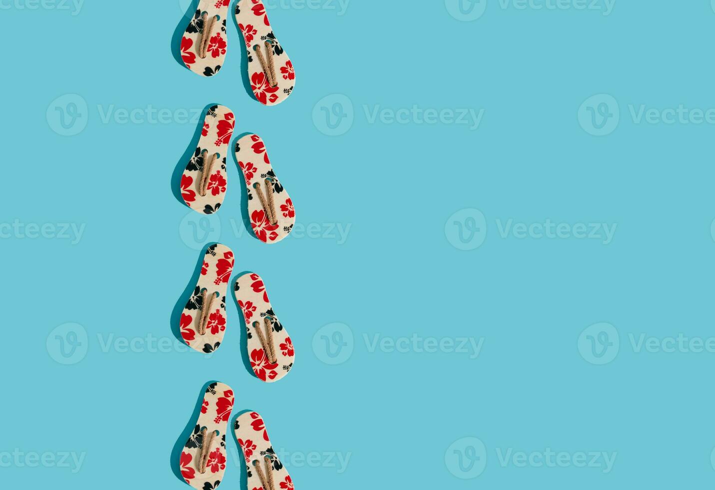 Creative sunlight summer composition made with floral slippers on bright blue background with copy space. Minimal summer concept. Trendy summer vacation idea. photo