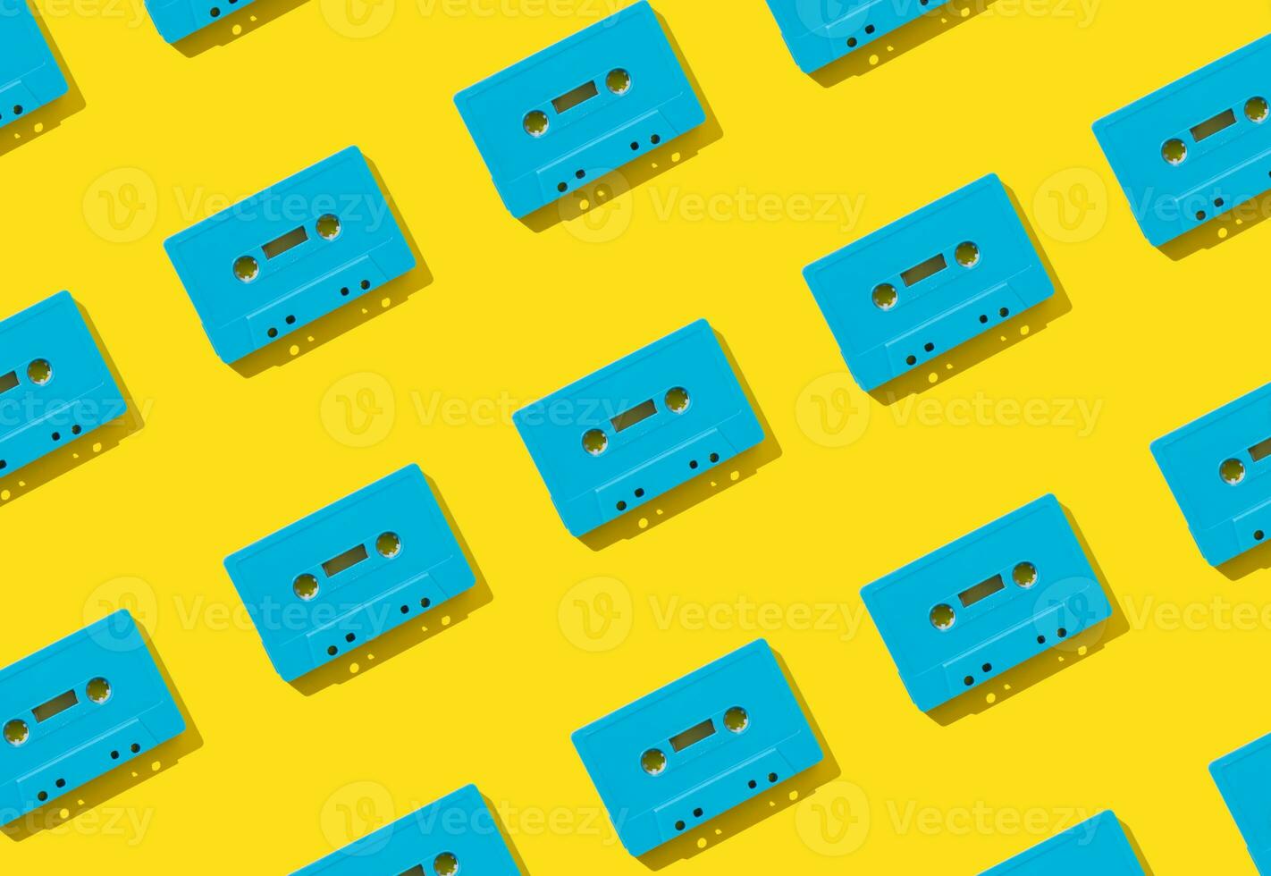 Pattern made with retro blue audio cassette tapes on yellow background. Creative concept of retro technology. 80's aesthetic. Vintage audio cassette tape pattern idea. Retro nostalgia. Flat lay. photo