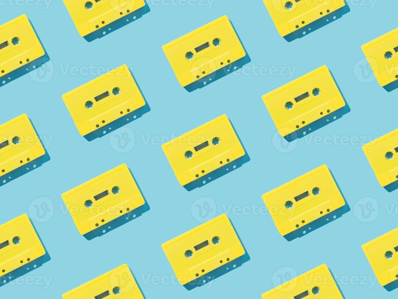 Pattern made with retro yellow audio cassette tapes on light blue background. Creative concept of retro technology. 80's aesthetic. Vintage audio cassette tape pattern idea. Retro nostalgia. Flat lay. photo