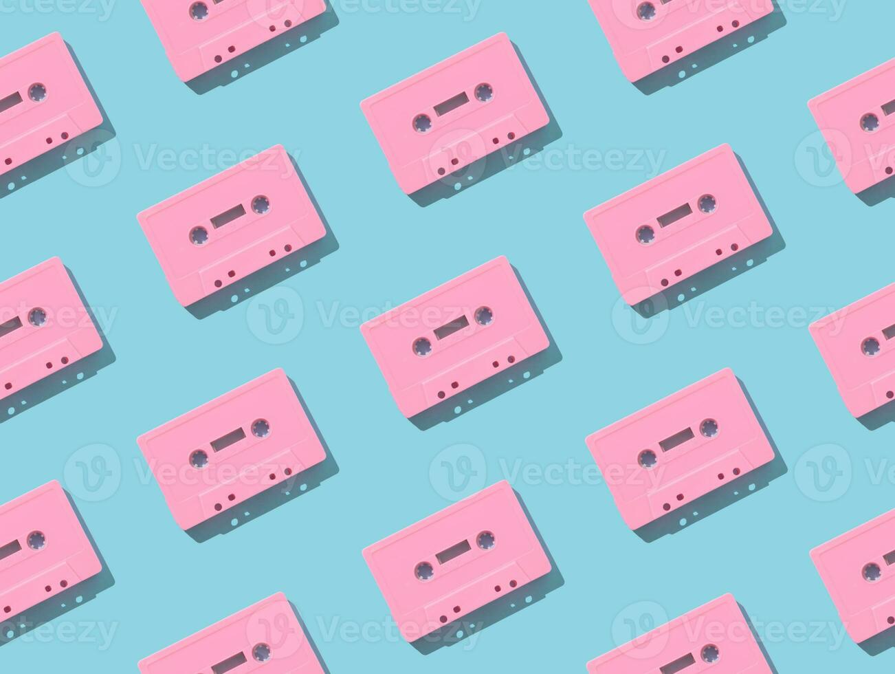 Pattern made with retro pink audio cassette tapes on light blue background. Creative concept of retro technology. 80's aesthetic. Vintage audio cassette tape pattern idea. Retro nostalgia. Flat lay. photo