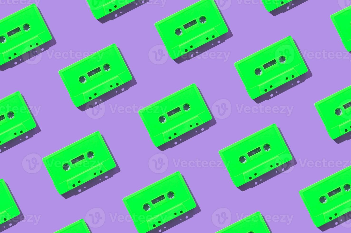 Pattern made with retro green audio cassette tapes on purple background. Creative concept of retro technology. 80's aesthetic. Vintage audio cassette tape pattern idea. Retro nostalgia. Flat lay. photo