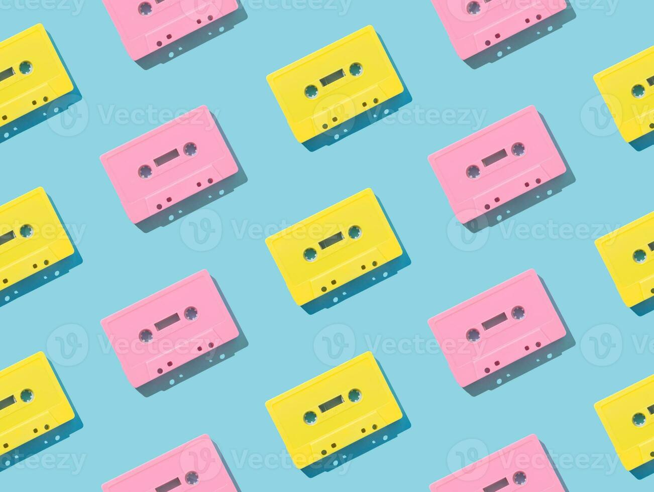 Pattern of retro pink and yellow audio cassette tapes on  blue background. Creative concept of retro technology. 80's aesthetic. Vintage audio cassette tape pattern idea. Retro nostalgia. Flat lay. photo