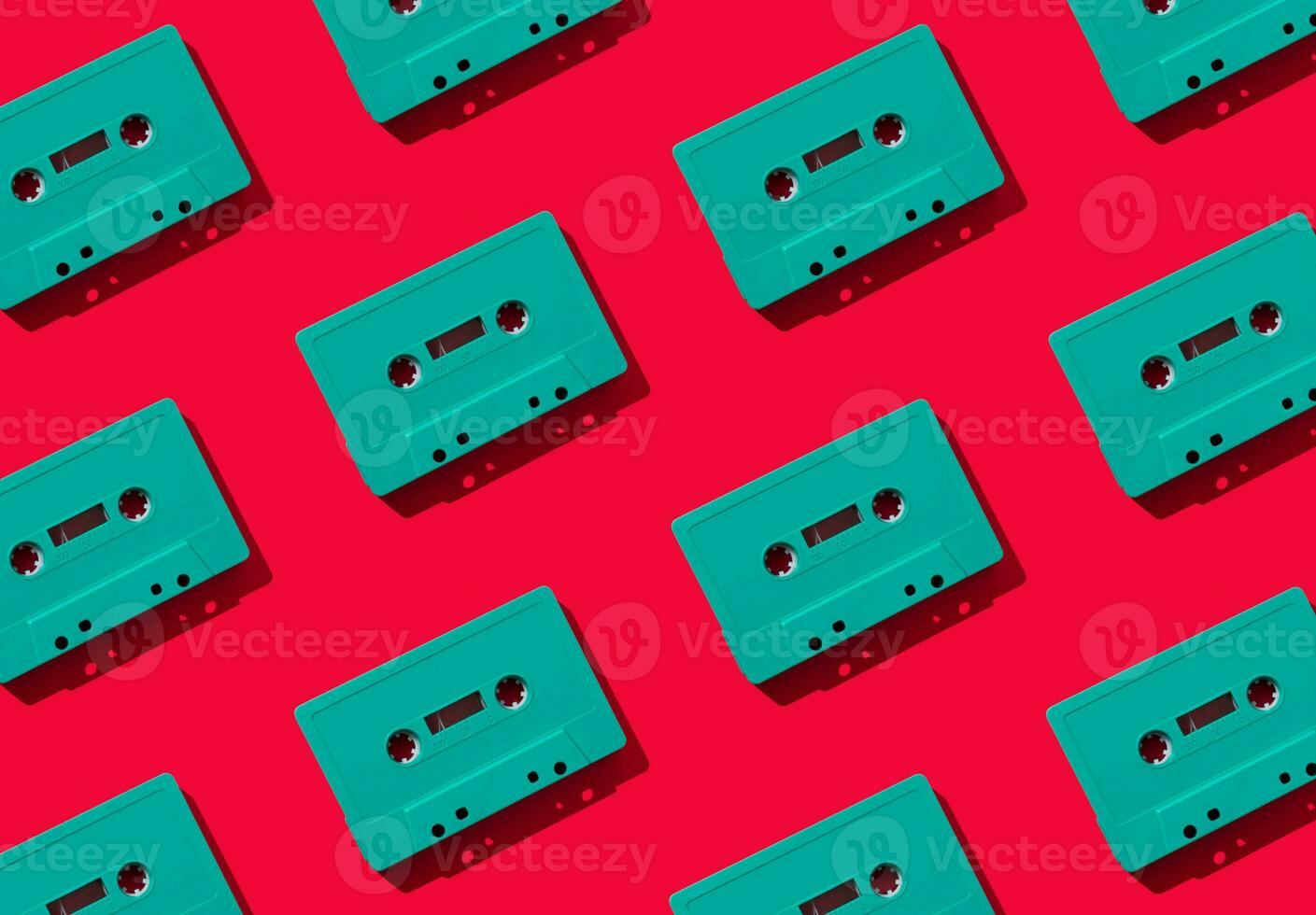 Pattern made with retro green audio cassette tapes on red background. Creative concept of retro technology. 80's aesthetic. Vintage audio cassette tape pattern idea. Retro nostalgia. Flat lay. photo