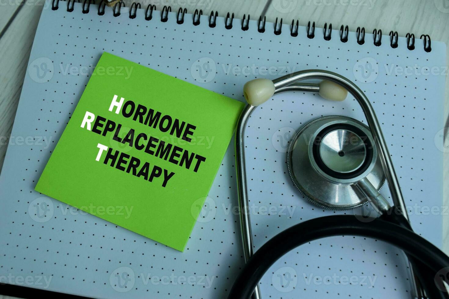 Concept of HRT - Hormone Replacement Therapy write on sticky notes with stethoscope isolated on Wooden Table. photo