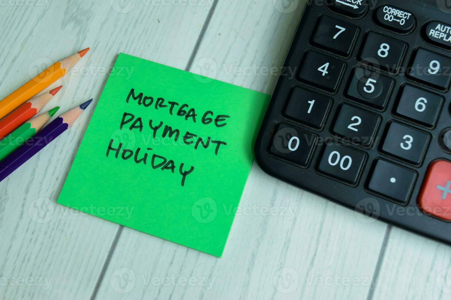 Concept of Mortgage Payment Holiday write on sticky notes with calculator isolated on Wooden Table. photo