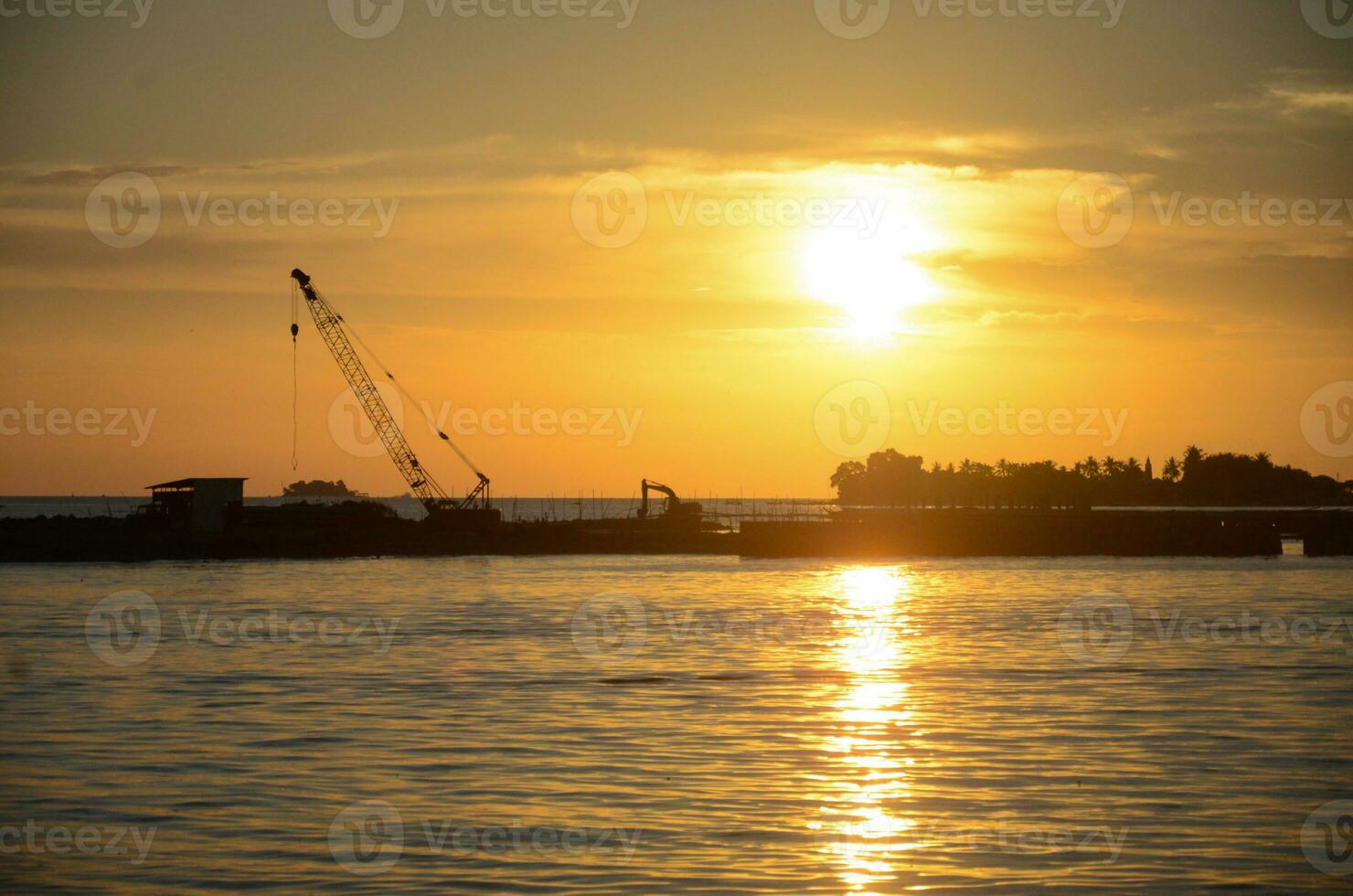 Silhouette construction boat and cranes setting in marine area to contract export pipeline business under to sea with beautiful sunset sky background. photo