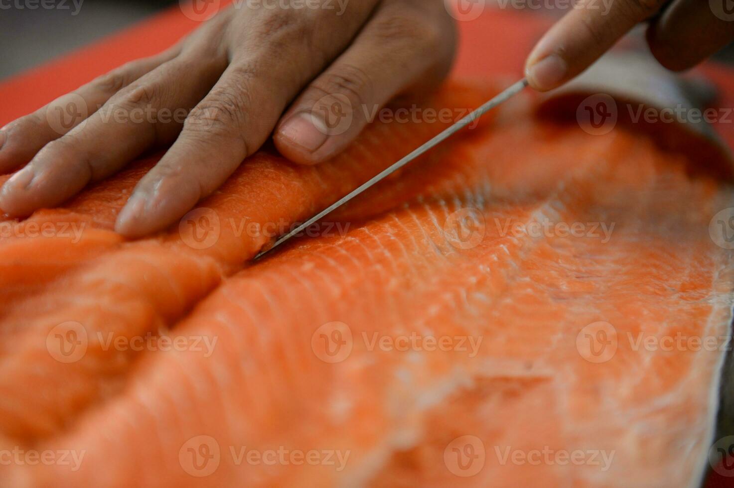 Fresh salmon fillet close-up on white cutting board table while filleting salmon belly by chef in cooking room photo