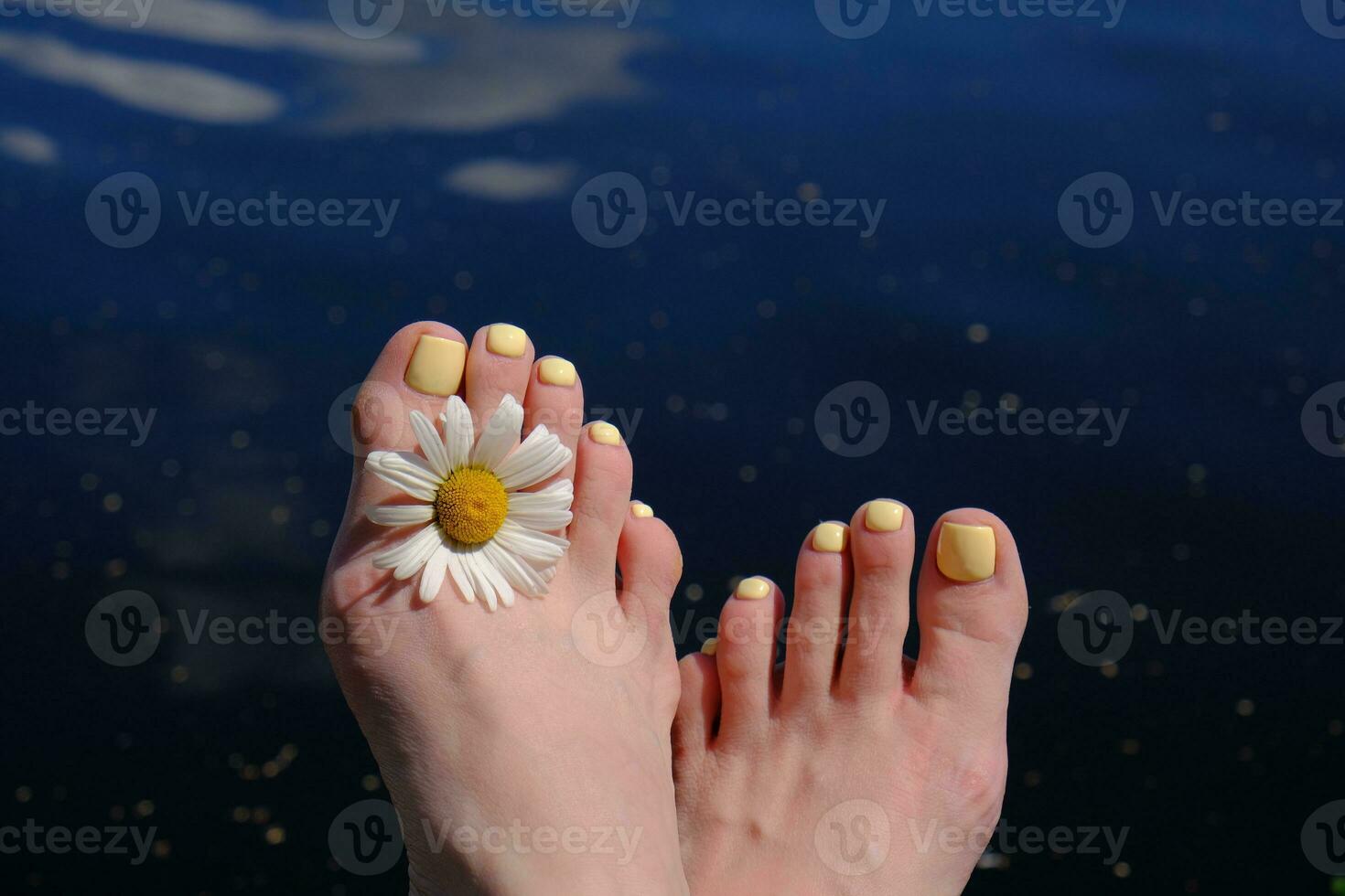 female feet with a yellow pedicure photo