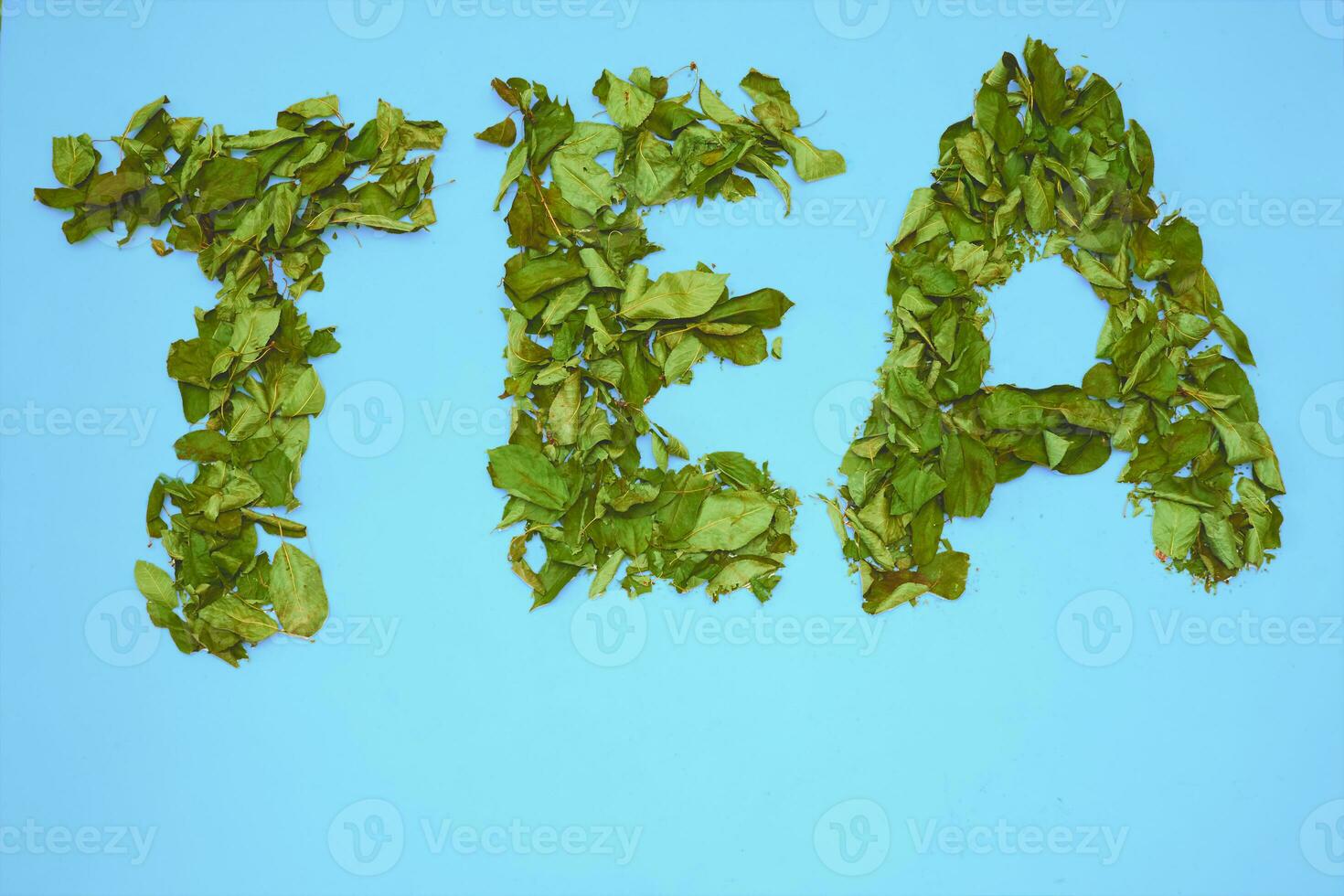 Inscription with letters Tea, dried herbal leaves of fruit trees on turquoise photo