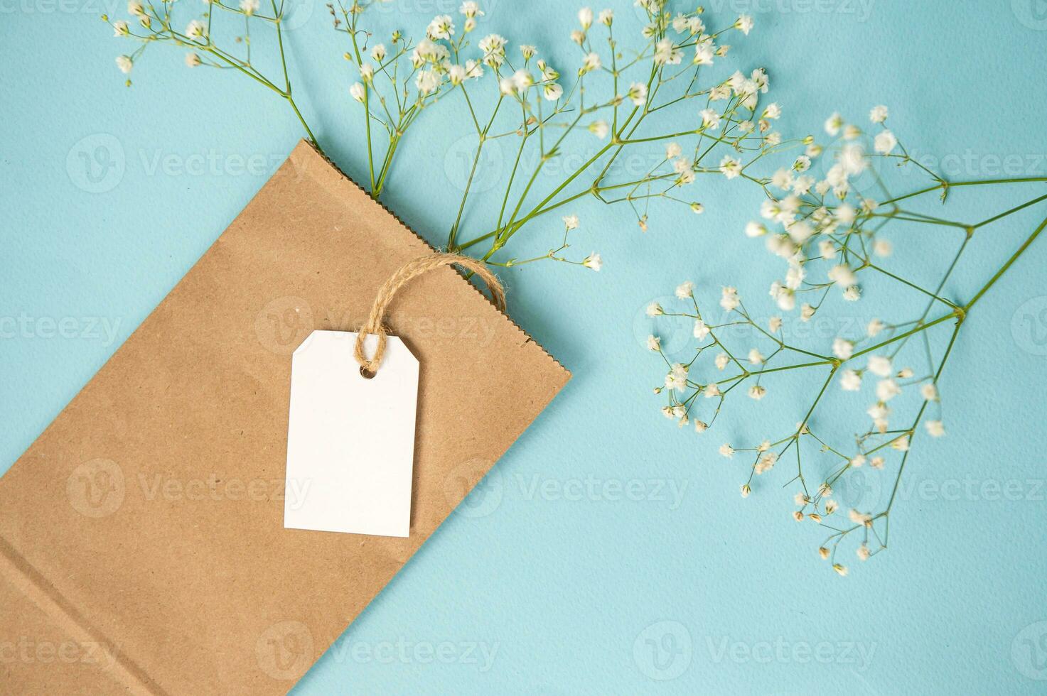 A mock-up of a white tag, label and price tag near a craft bag with flowers lie on a colorful yellow table photo
