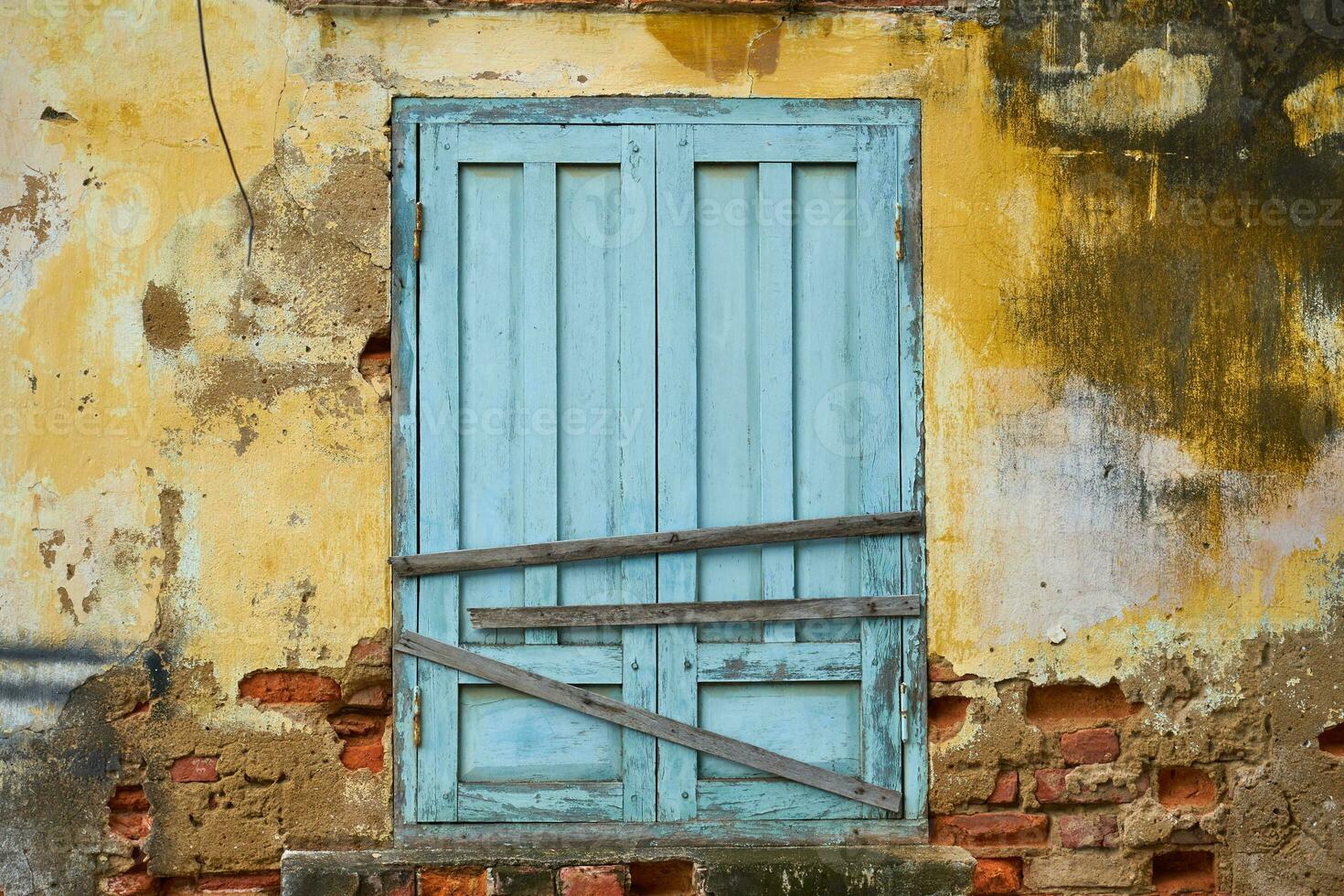 A blue boarded-up door on a vintage wall of an old building. photo