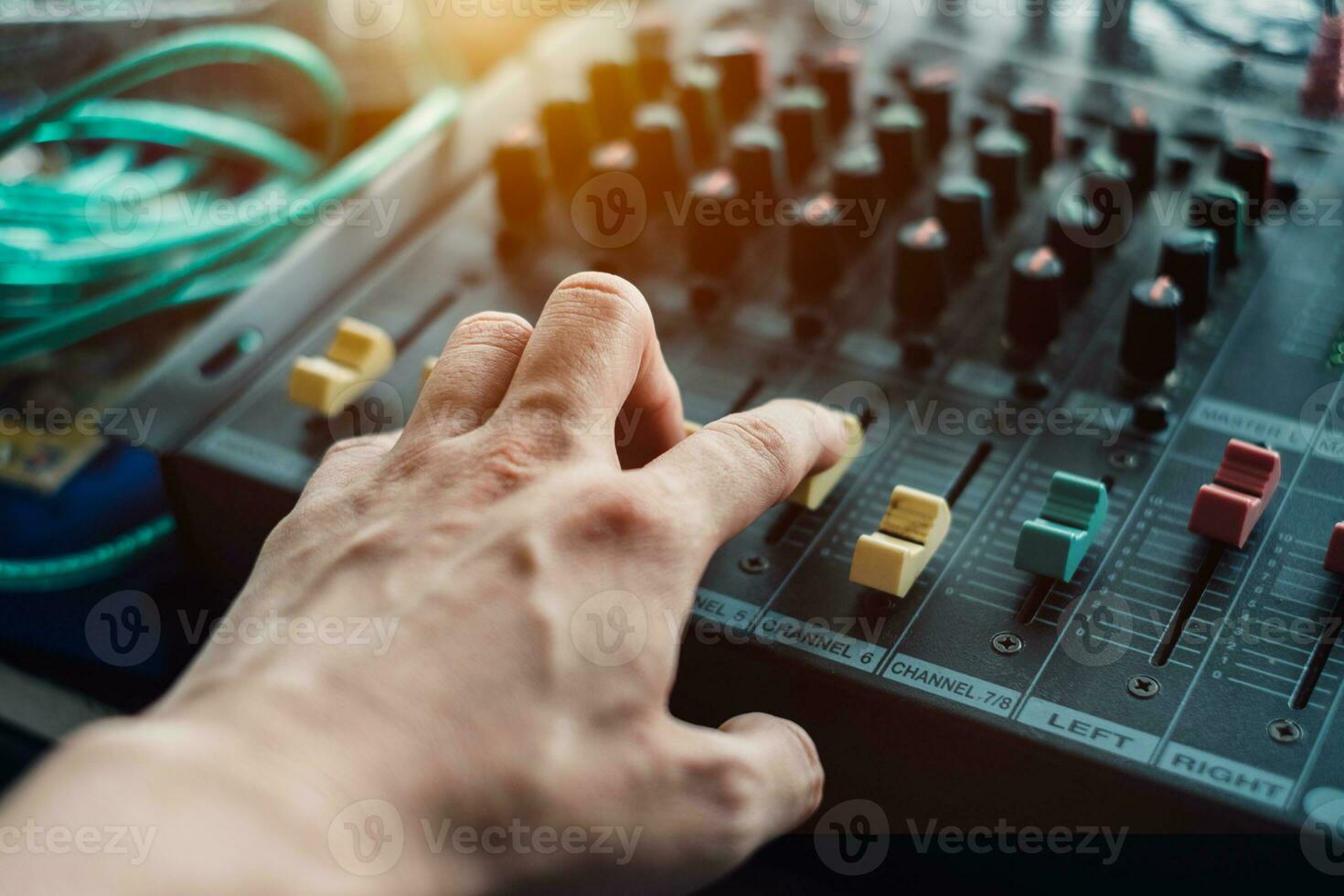 Close-up hand adjusting mixer sound on audio panel photo