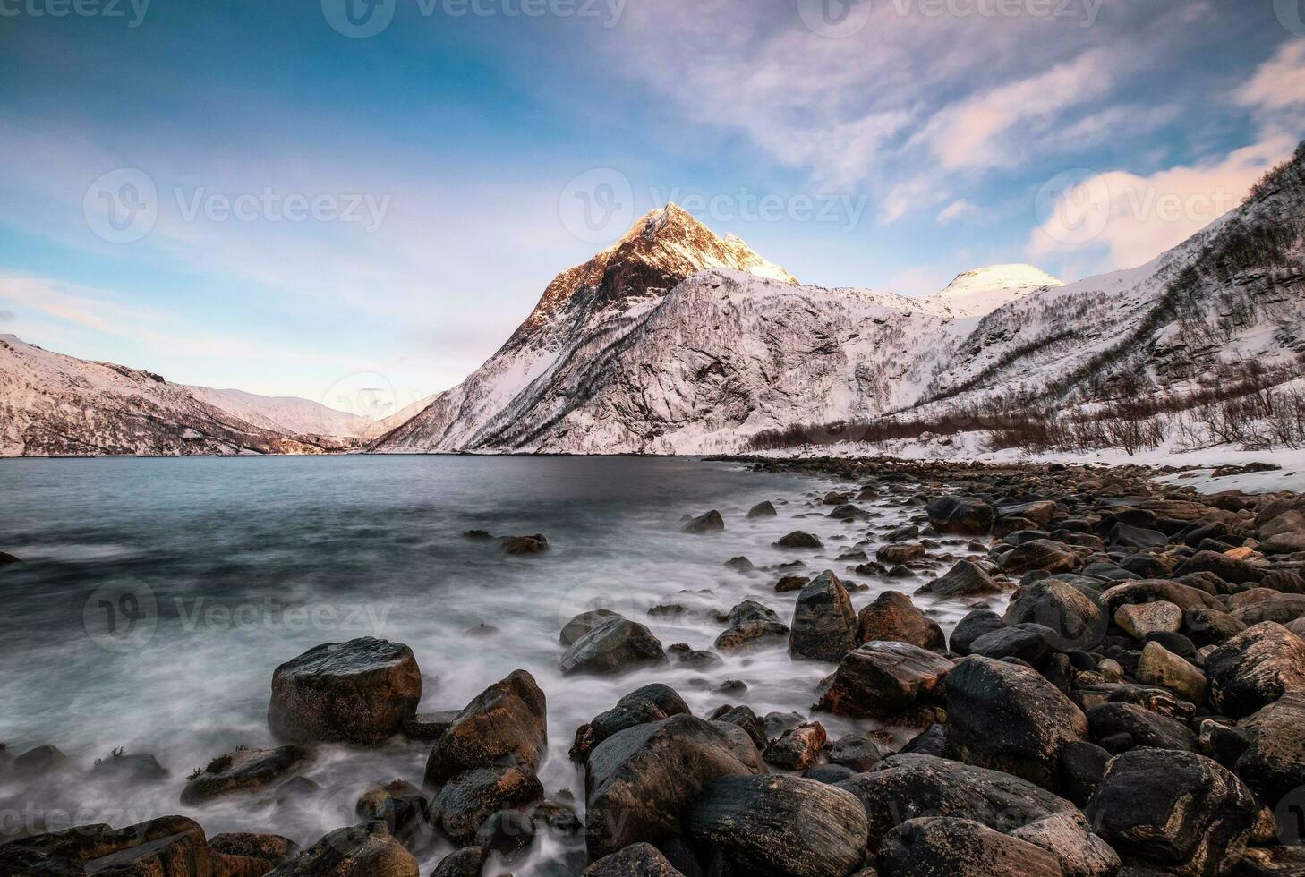 Seascape wave hitting on rocks with mountains on senja island photo