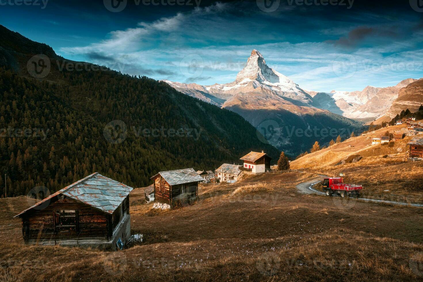 Matterhorn mountain with truck driving on the road and wooden huts on the hill in the morning on autumn at Zermatt, Switzerland photo