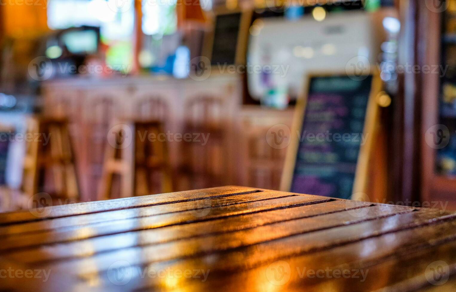 Glossy wooden table top on blurred counter bar glowing in restaurant photo