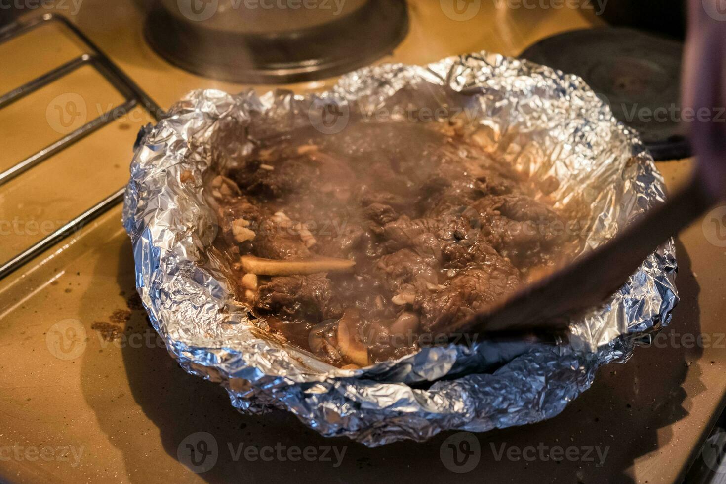 Wooden flipper frying steak beef in foil photo