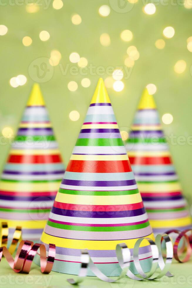 Striped colored party hats on green background. Holiday party. Close-up. photo