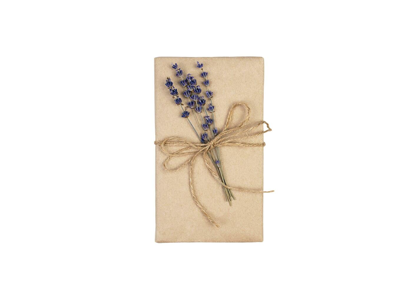 Gift wrapped in eco paper decorated with a sprig of lavender isolated on a white background. Holidays concept. Top view. Close-up. photo
