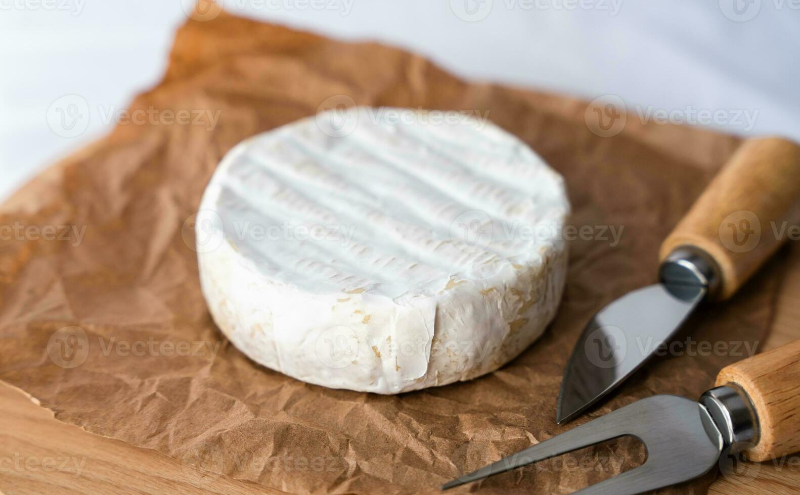 French soft cheese with white mold Camembert and knives for cutting cheese on the kitchen table. Close-up. Selective focus. photo