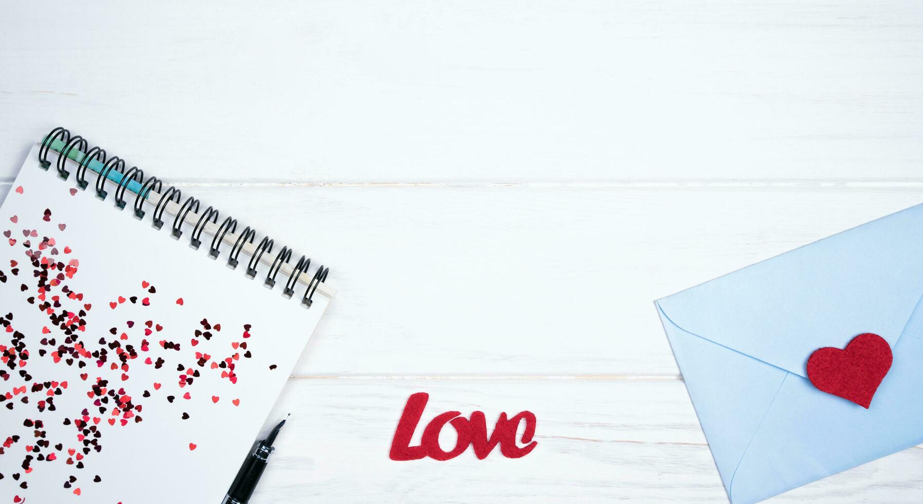 Notepad, pen, envelope and red hearts for congratulations on Valentine's Day. Romantic message. Flatlay. Top view. Place for text. photo